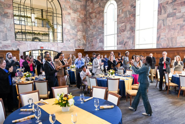 Attendees giving a standing ovation at an EmWELL Micro-Funding awards event in a banquet hall