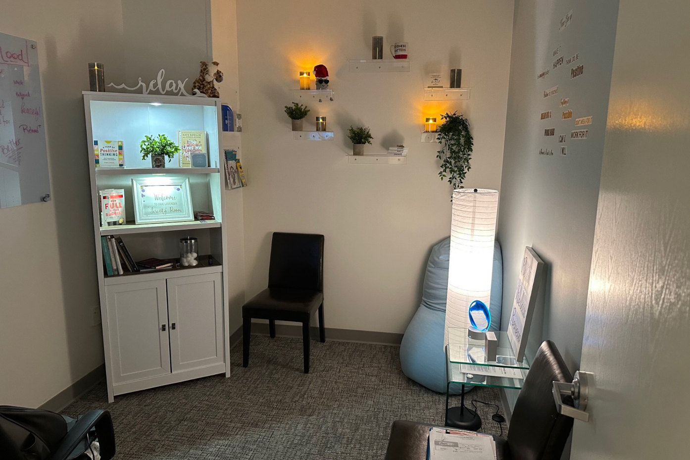 A wellness relaxation room with a bookshelf, bean bag chair, ambient lighting, and motivational wall decals, created through an EmWELL Micro-Funding project